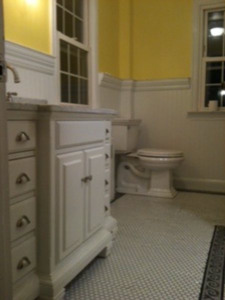 Bathroom with a white raised-panel vanity, beadboard wainscot and yellow walls