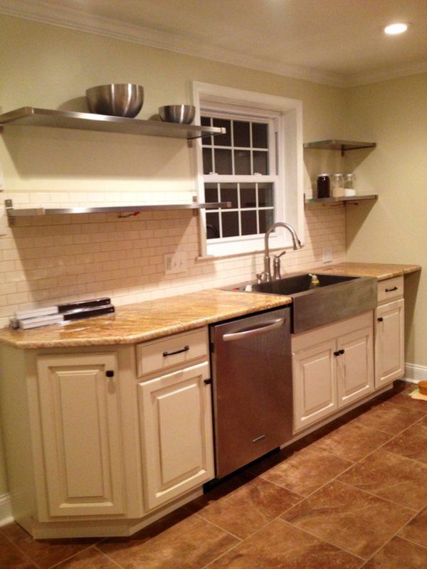 After: the same sink wall with cream glazed cabinets, open steel shelving, subway tile and a farmhouse sink