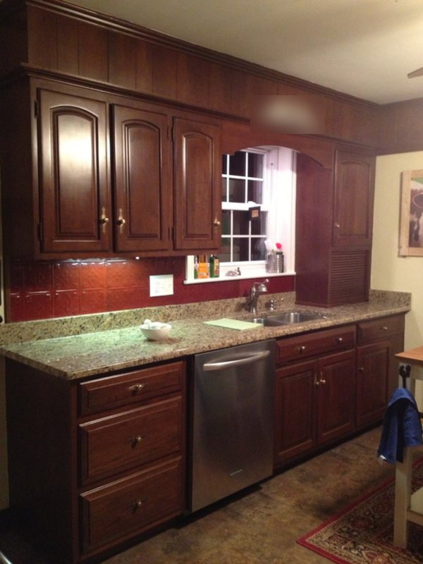 Before: dark wood cabinets, red tin backsplash and dated lighting along the sink wall