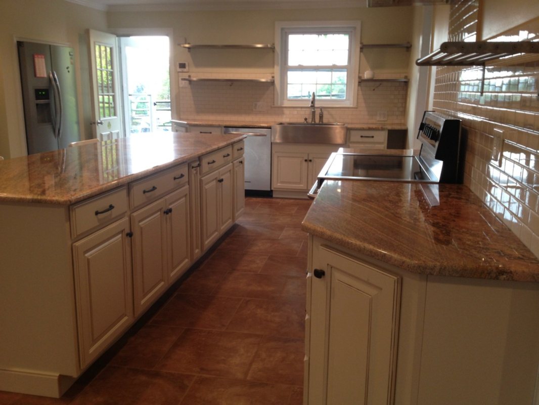 Finished kitchen with a long granite island facing the range wall and glossy subway tile